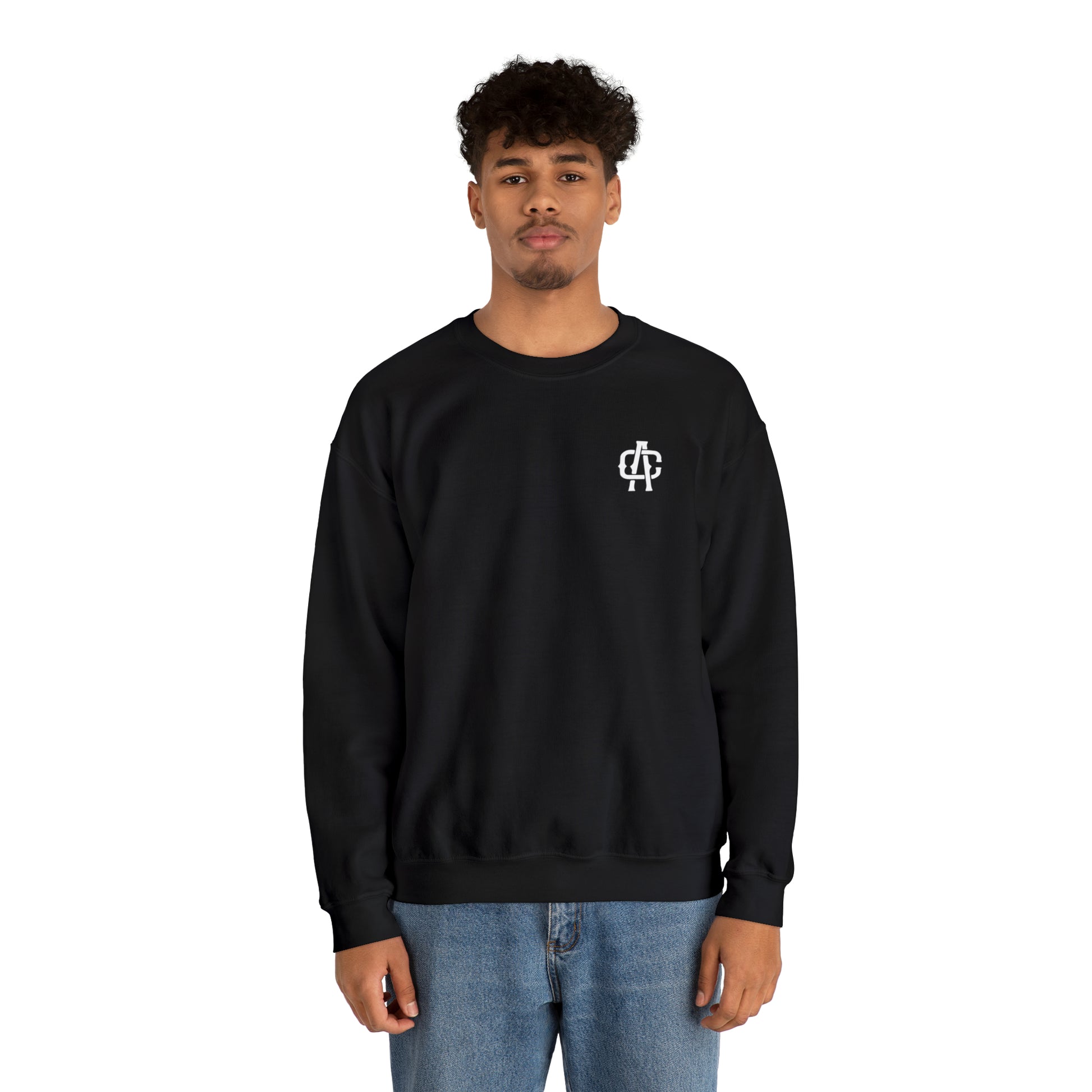 Man wearing a black heavy blend crewneck sweatshirt with a small white logo on the chest and blue jeans.