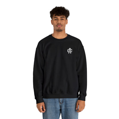 Man wearing a black heavy blend crewneck sweatshirt with a small white logo on the chest and blue jeans.