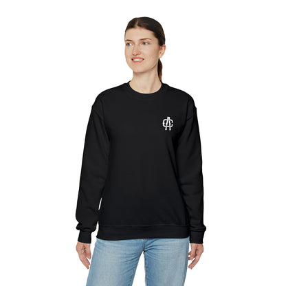 Woman wearing a black heavy blend crewneck sweatshirt with a small white logo on the chest, isolated on white.