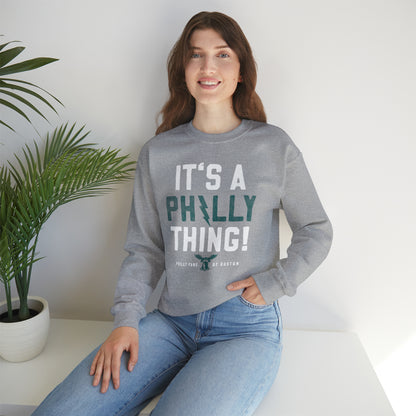 Woman wearing a grey crewneck sweatshirt with It's a Philly Thing text, featuring a ribbed collar and loose fit.