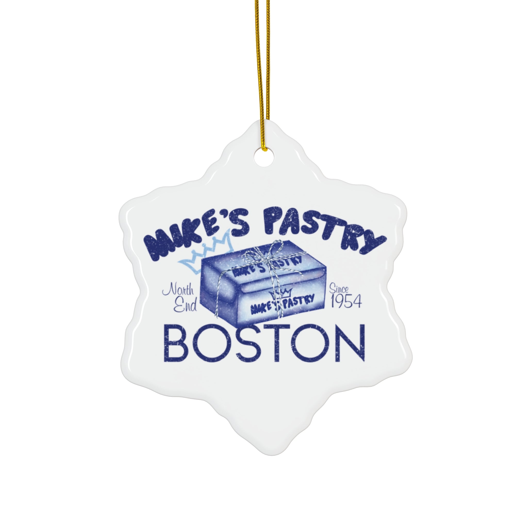 Glossy white ceramic snowflake ornament featuring a blue Mike's Pastry Boston 1954 design with a gold hanging string.