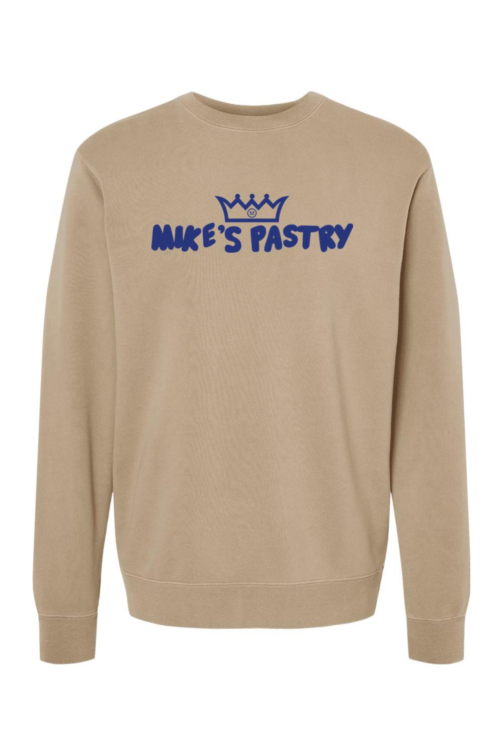 Tan pigment-dyed crewneck sweatshirt with blue Mike's Pastry logo and crown graphic on the chest.