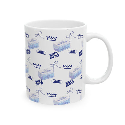 11oz white ceramic mug featuring a blue Mike's Pastry box, crown, and cannoli pattern with a comfortable C-handle.