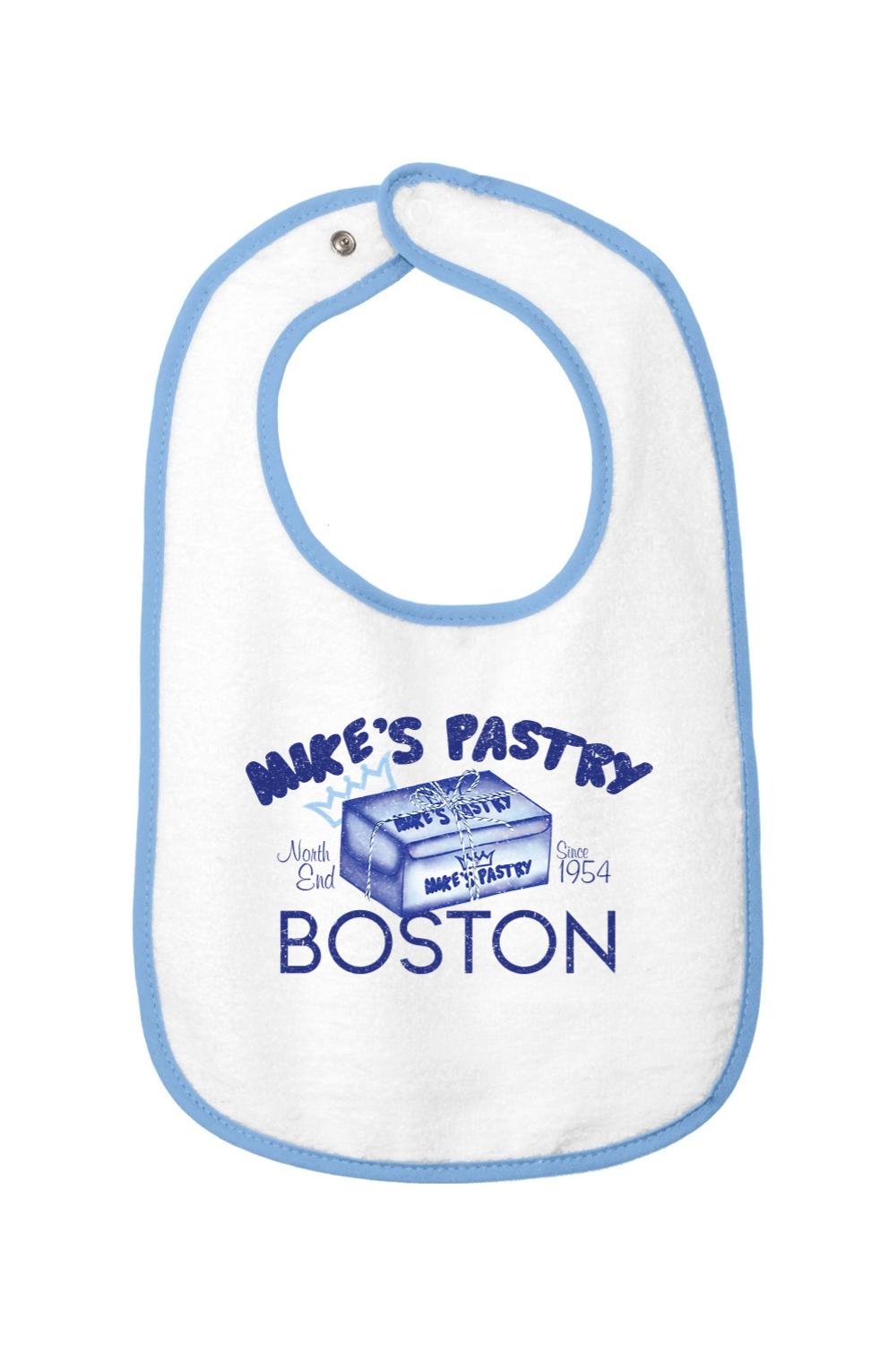 White cotton terry baby bib with blue trim, featuring a Mike's Pastry Boston box graphic and hook-and-loop closure.