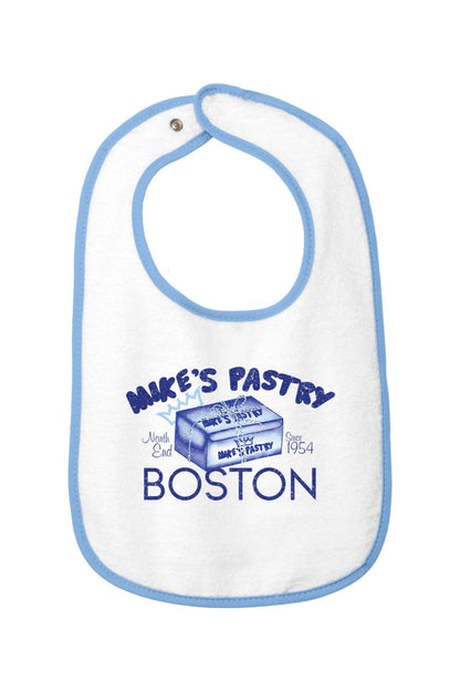 White cotton terry baby bib with blue trim, featuring a Mike's Pastry Boston box graphic and hook-and-loop closure.
