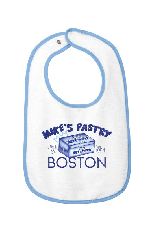 White cotton terry baby bib with blue trim, featuring a Mike's Pastry Boston box graphic and hook-and-loop closure.