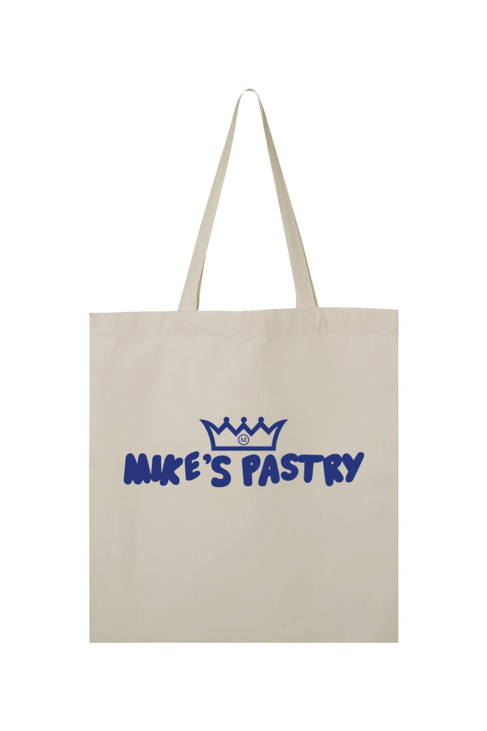 Beige canvas tote bag featuring a blue Mike's Pastry logo with a crown icon and dual shoulder straps.