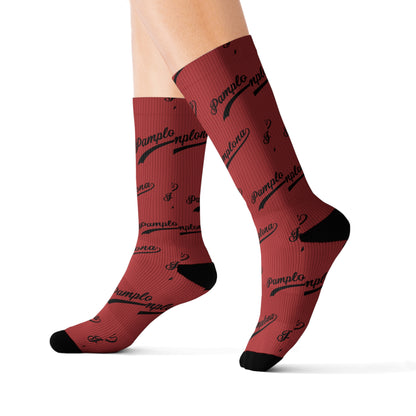 Unisex Pamplona crew socks in red with black script print, ribbed texture, and cushioned black heel and toe.