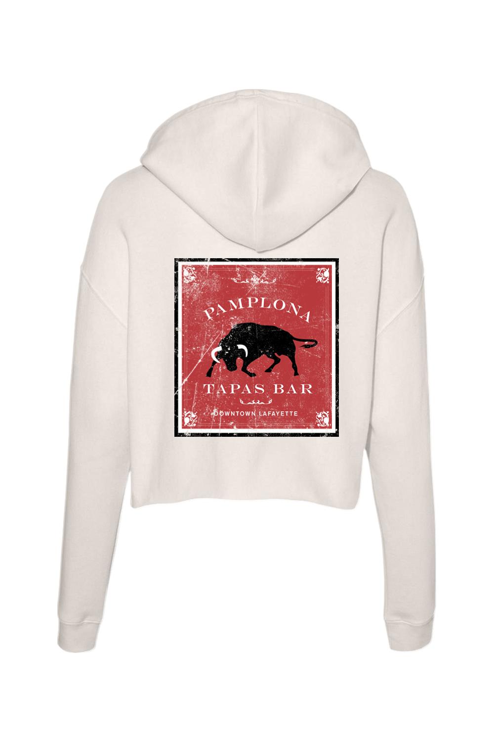 Cream-colored cropped hoodie featuring a red and black Pamplona Tapas Bar bull graphic on the back.