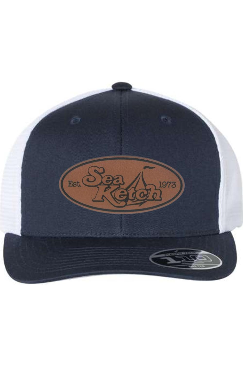 Navy and white trucker cap with a brown oval leather patch featuring the Sea Ketch logo and a Flexfit 110 sticker.