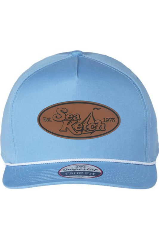 Light blue five-panel cotton twill hat with a brown leather Sea Ketch logo patch and white decorative rope trim.