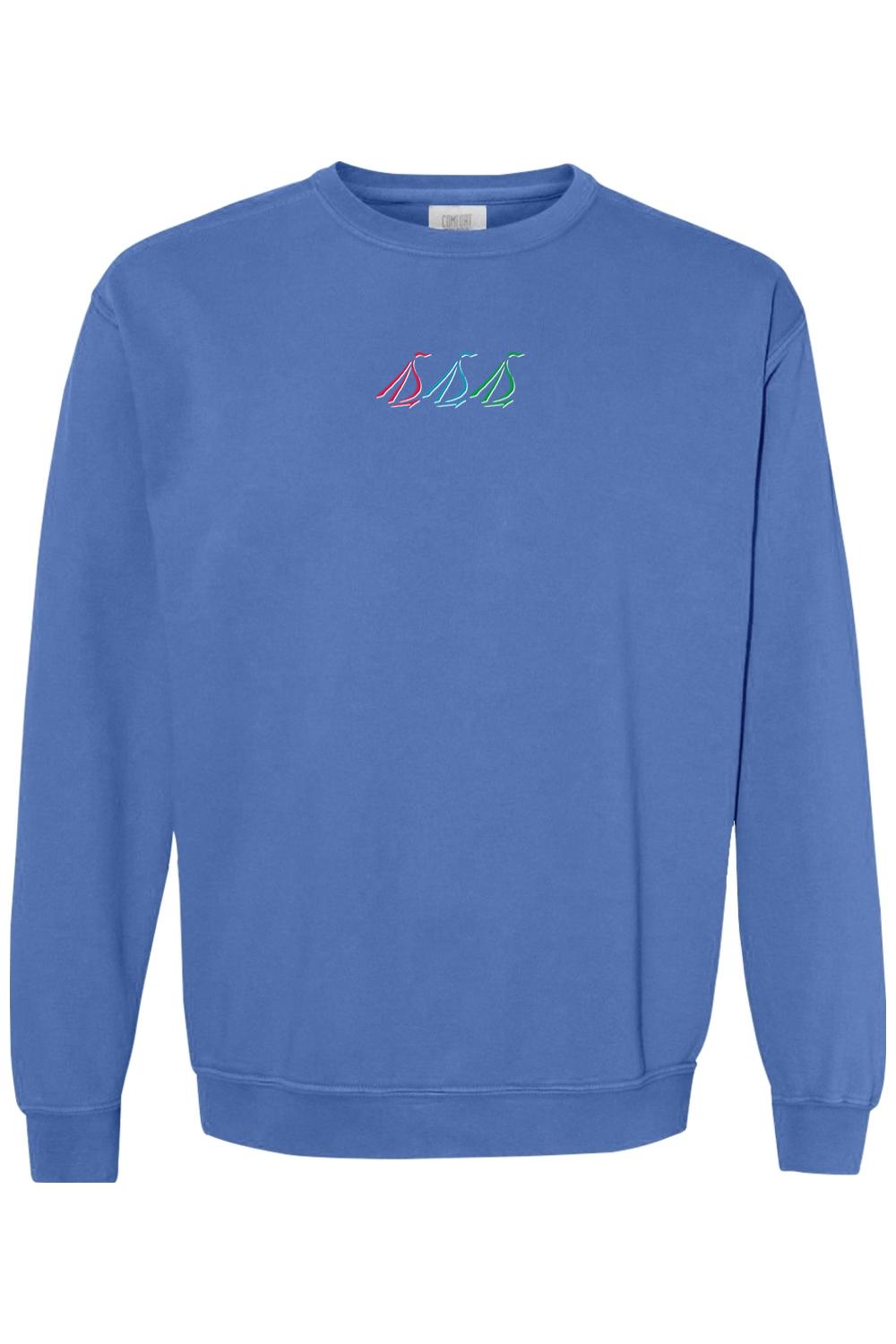 Blue Comfort Colors crewneck sweatshirt featuring a small, colorful tri-sail nautical graphic on the chest.