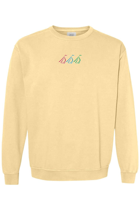 Butter yellow Comfort Colors crewneck sweatshirt featuring a small, colorful embroidered tri-sail nautical logo.