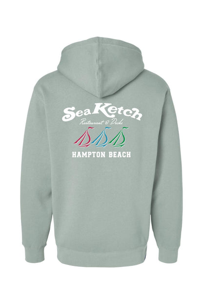 Sage green heavyweight hoodie featuring a Sea Ketch Hampton Beach logo with three colorful sailboats on the back.