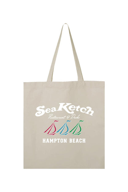 Beige canvas tote bag featuring a Sea Ketch Restaurant & Decks logo with three colorful sailboat icons.