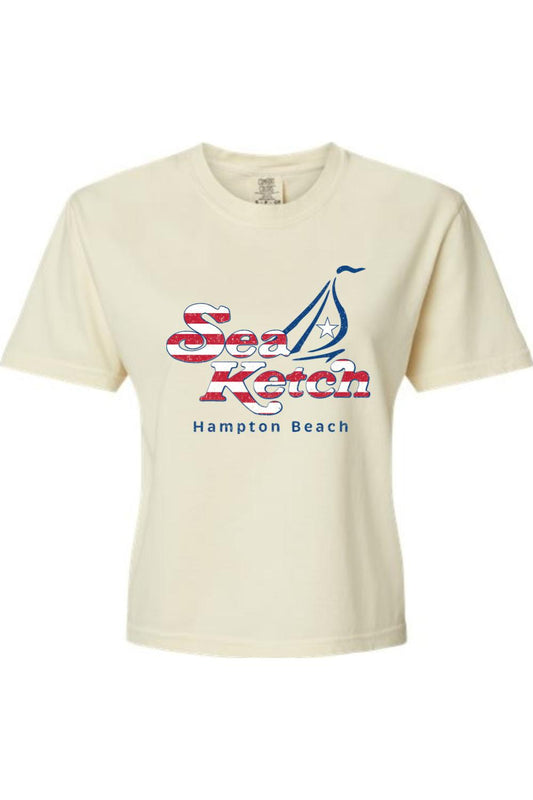 Cream-colored Comfort Colors boxy t-shirt featuring a red, white, and blue Sea Ketch Hampton Beach sailboat graphic.