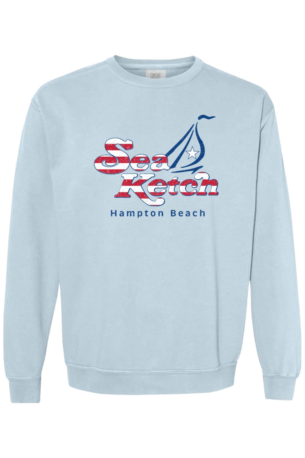 Light blue Comfort Colors crewneck sweatshirt featuring a red, white, and blue Sea Ketch Hampton Beach sailboat logo.