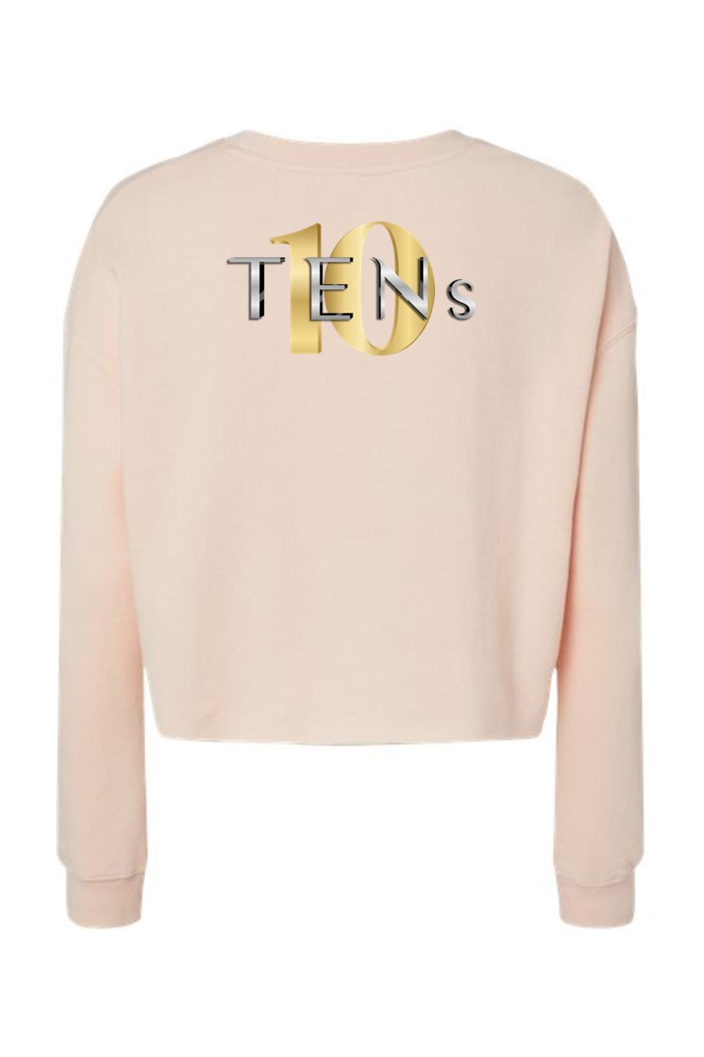 Light pink cropped sweatshirt with long sleeves and a gold and silver TENS logo graphic on the back.