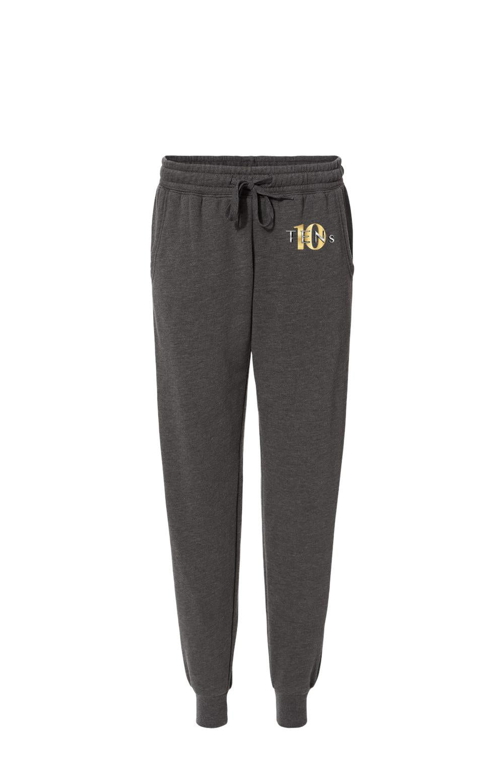 Charcoal grey cotton sweatpants with a drawstring waist, ribbed cuffs, and a gold Tens Show Club logo on the hip.