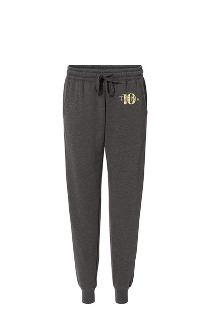 Charcoal grey cotton sweatpants with a drawstring waist, ribbed cuffs, and a gold Tens Show Club logo on the hip.