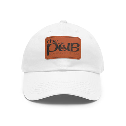 White dad hat with a brown faux leather patch featuring The Pub Somerville logo and a pre-curved bill.