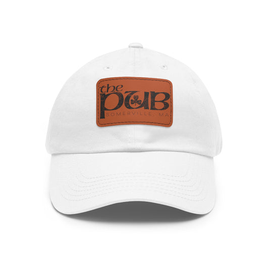 White dad hat with a brown faux leather patch featuring The Pub Somerville logo and a pre-curved bill.