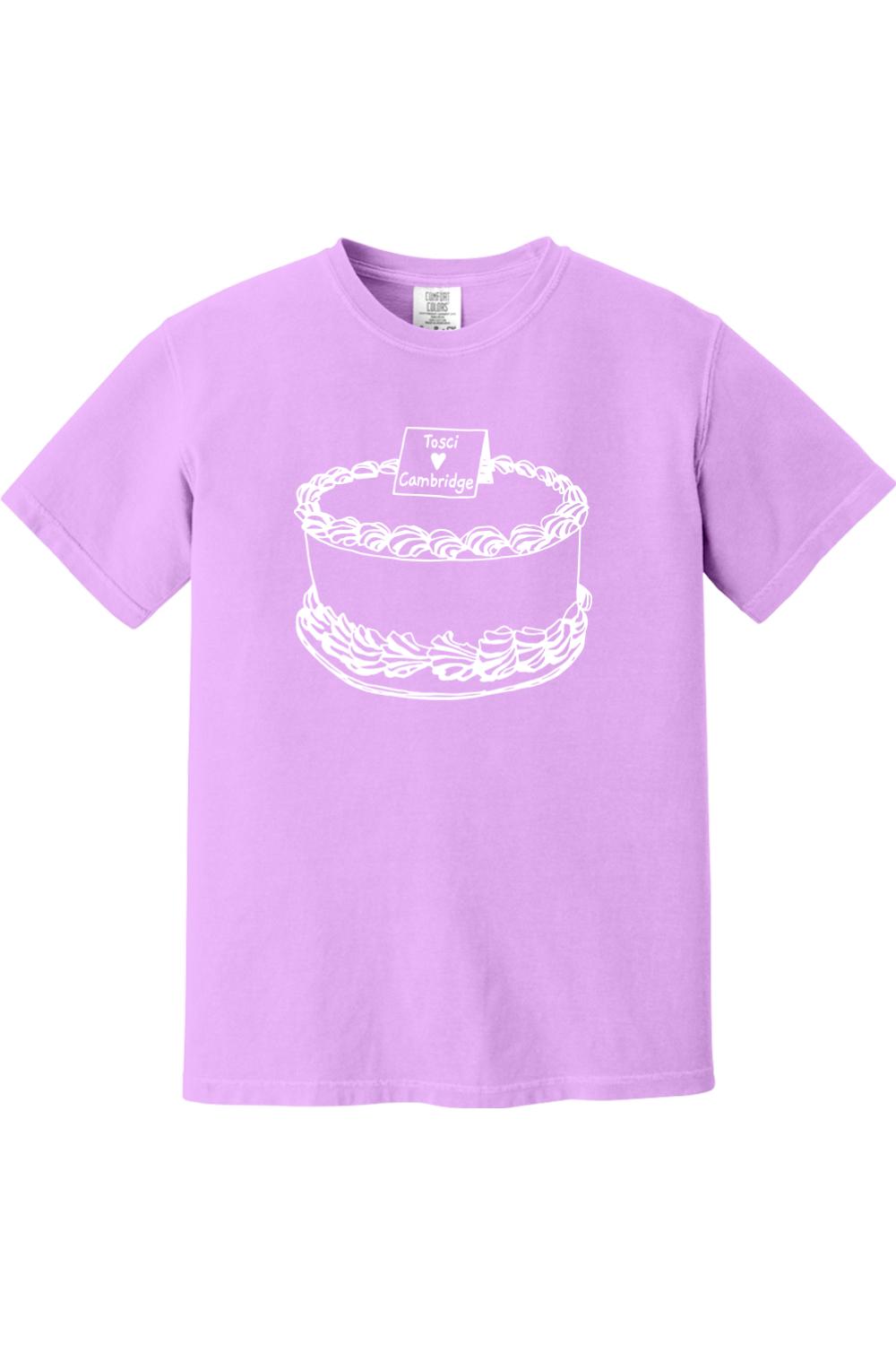 Light purple Comfort Colors short sleeve t-shirt featuring a white line art graphic of a cake with Tosci Cambridge text.