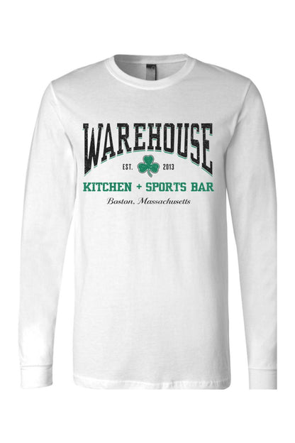 White long-sleeve cotton t-shirt featuring a green Warehouse Kitchen + Sports Bar Boston clover logo graphic.