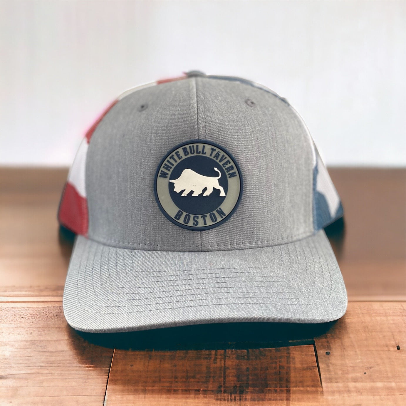 Heather gray trucker hat with a White Bull Tavern PVC patch and American flag printed mesh back.