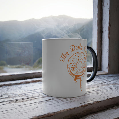 11oz heat-reactive ceramic mug with a white exterior, black handle, and orange donut graphic on a rustic windowsill.